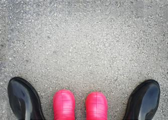 Grey background with asphalt texture, adults and children rubber boots