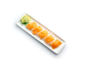 pieces of red fish with lemon and herbs on a rectangular plate on an isolated white background