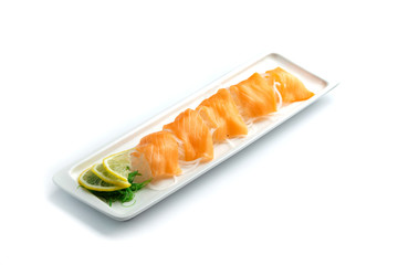 pieces of red fish with lemon and herbs on a rectangular plate on an isolated white background