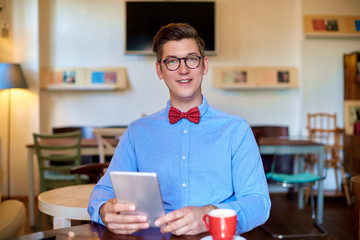 Young coffee shop owner businessman working on his digital tablet