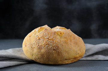 Wheat bread with cornmeal and carrot pieces. The concept of natural and biological products. Dark background. Close-up. 