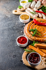 Set of various sausages ready for grilling, with different sauces, black concrete background copy space