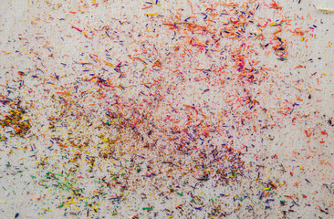 Colorful pencil shavings on wooden background.