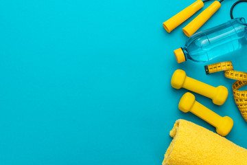 flat lay photo of yellow fitness equipment in oder over turquoise blue backgound