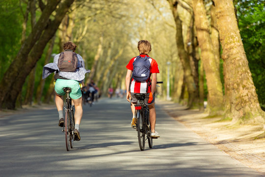 Boys with backpacks biking in the Amsterdam Vondelpark.