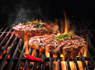 Beef steaks sizzling on the grill - obrazy, fototapety, plakaty