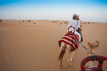 camel riding in desert sand. UAE