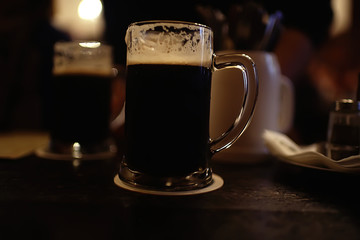 mug of dark beer in the interior of  pub / pint of beer with foam on a served table in  beer restaurant in Czech Republic