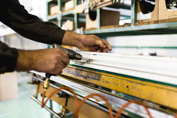 Factory for aluminum , wooden and PVC windows and doors production. Manual worker assembling PVC doors and windows. Selective focus.
