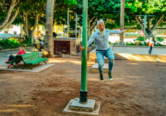 Smiling senior man relaxing in the park. Mature male having fun and  jumps like a child.- Focus on this face - Image