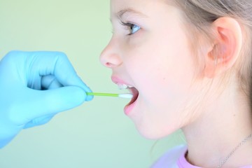 pediatrician using a cotton swab to take a sample from a girl throat. close up of scientist hand holding swab to collect dna of a little patient. making research a test dna molecule structure