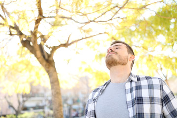 Man relaxing breathing deep fresh air in a park