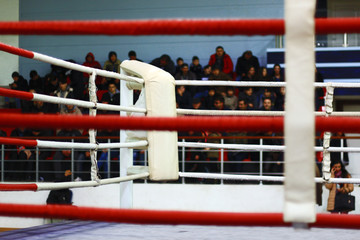Empty boxing ring with red ropes.