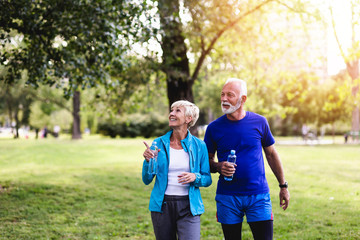 Happy senior couple enjoying in walk outdoors in park.