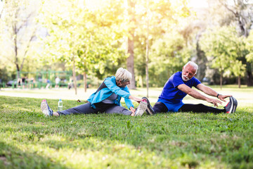 Happy fit senior couple exercising in park.