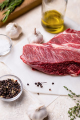 Raw cut of beef with herbs on light beige background