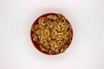 Walnut Kernels In Red Bowl (Other Names: Juglans Regia, Persian Walnut, English Walnut, Circassian Walnut). Isolated Image On A White Background