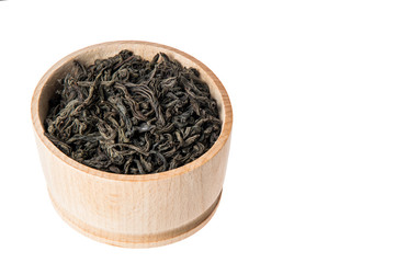 Close up. Wooden brown bowl with large leaf dried black tea. Isolated on white background. Copy space.