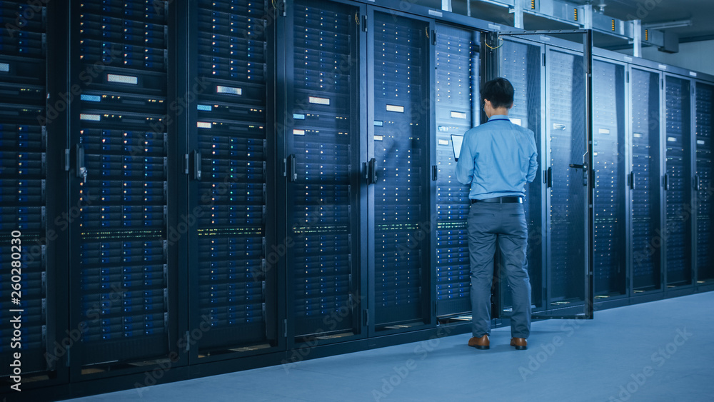 Aufkleber In Data Center: Male IT Technician Running Maintenance Programme on a Laptop, Controls Operational Server Rack Optimal Functioning. Modern High-Tech Telecommunications Operational Super Computer.