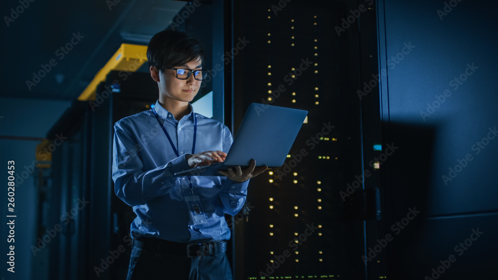 Poster In Dark Data Center: Male IT Specialist Stands Beside the Row of Operational Server Racks, Uses Laptop for Maintenance. Concept for Cloud Computing, Artificial Intelligence, Cybersecurity. Neon Lights