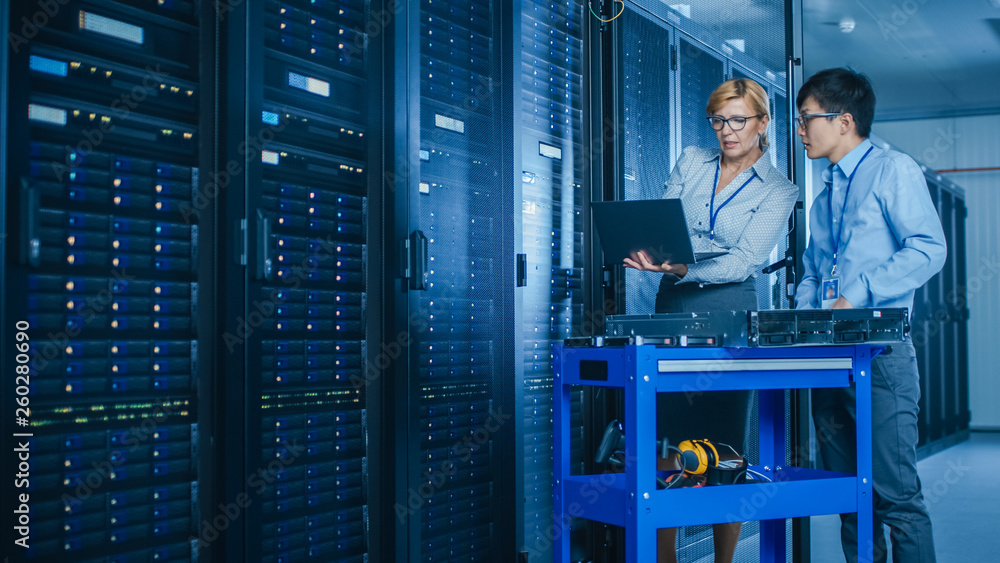 Aufkleber In the Modern Data Center: Engineer and IT Specialist Work with Server Racks, on a Pushcart Equipment for Installing New Hardware. Specialists Doing Maintenance and Diagnostics of the Database.