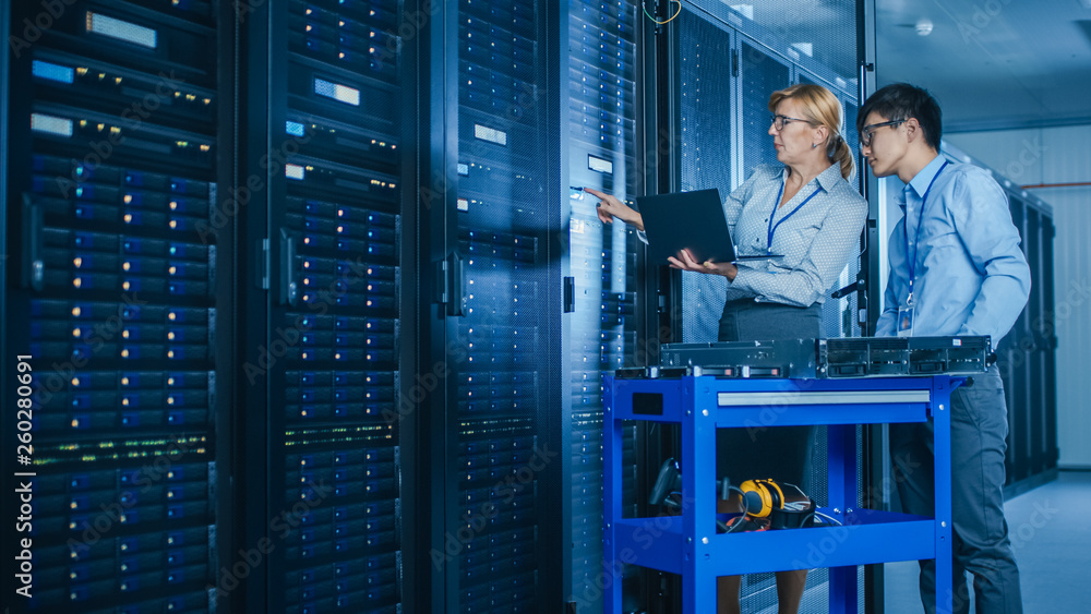 Aufkleber In the Modern Data Center: Engineer and IT Specialist Work with Server Racks, on a Pushcart Equipment for Installing New Hardware. Specialists Doing Maintenance and Diagnostics of the Database.