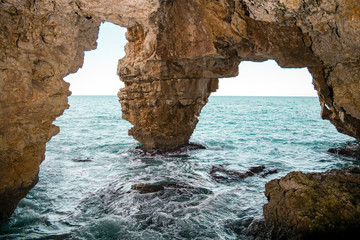 cueva con arco natural en la costa, a pie de mar. 
