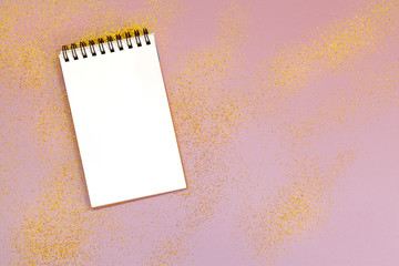 Empty pad with gold sparkles, stars and glitters on pink background.