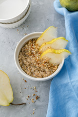Healthy oatmeal porridge in  bowl with sliced pear for breakfast