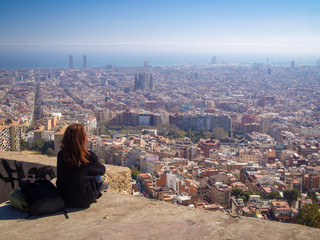 Lonely tourist girl sitting and watching the aerial skyline view of Barcelona (Spain) from the...