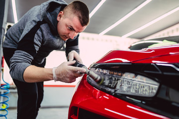 Car detailing - Worker with orbital polisher in auto repair shop.