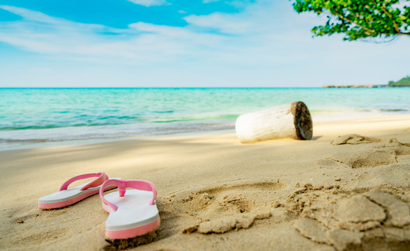 Pink and white sandals on sand beach. Casual style flip-flop were removed at seaside. Summer vacation on tropical beach. Fun holiday travel on sandy beach. Summertime. Summer vibes. Relaxing time.