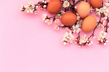 Fototapeta na wymiar Easter pink background with chicken eggs and spring flowers. Top view with copy space.