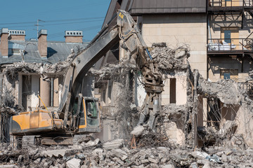Excavator with hydraulic shears for dismantling the ruins of the house, demolition.