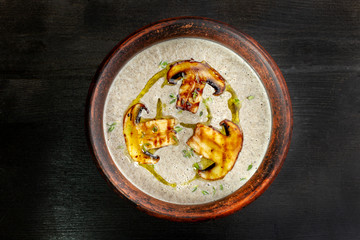 Cream soup with mushrooms champignon, dishes made of natural clay.