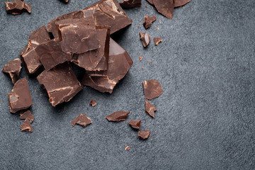 Dark or milk organic chocolate pieces on dark concrete backgound