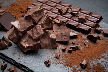 Dark or milk organic chocolate pieces on dark concrete backgound