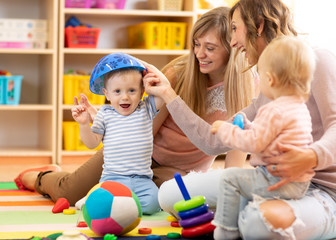 Mothers with kids play in playroom