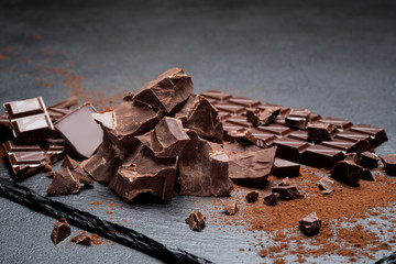 Dark or milk organic chocolate pieces on dark concrete backgound