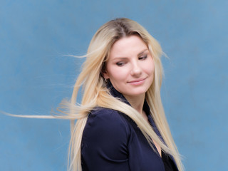 Portrait of happy smiling young cheerful businesswoman standing with flowing hair. Success in business concept studio shot. Blue suit.