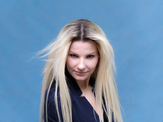 Portrait of happy smiling young cheerful businesswoman standing with flowing hair. Success in business concept studio shot. Blue suit.