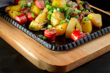 Fried potatoes with mushroom and sausage in cast iron frying pan.