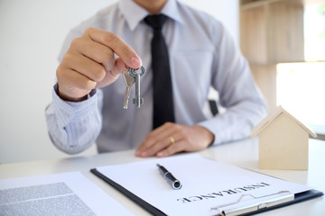 Sales manager giving advice application form document, considering mortgage loan offer for car and house insurance.