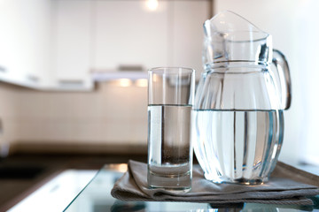 A glass of fresh water with crafin on the background of a modern kitchen.