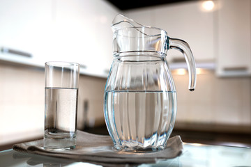 A glass of fresh water with crafin on the background of a modern kitchen.