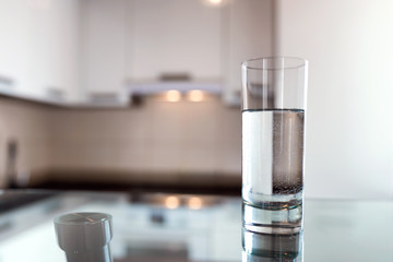 A glass of fresh water on the background of a modern kitchen.