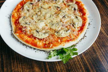 Hot pizza slice with melting cheese on a wooden table.