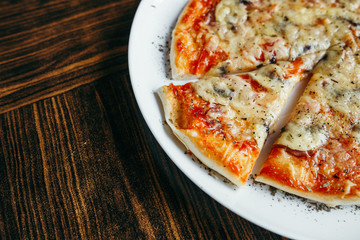 Hot pizza slice with melting cheese on a wooden table.