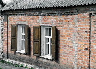 Windows with wooden shutters in a rustic brick house