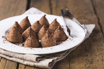 Homemade Chocolate Truffles With Cocoa Powder on a White Plate Old Wooden Background Tasty Candy Horizontal